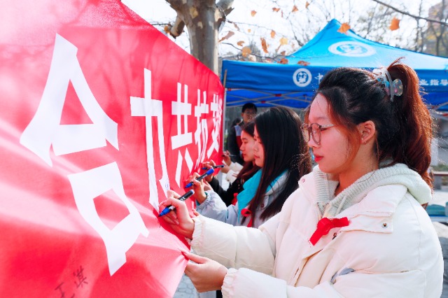 20231127中國石油大學(xué)（華東）青年學(xué)子在合力共抗艾滋的條幅上簽字，表達(dá)抗擊艾滋病的決心和信心  .jpg