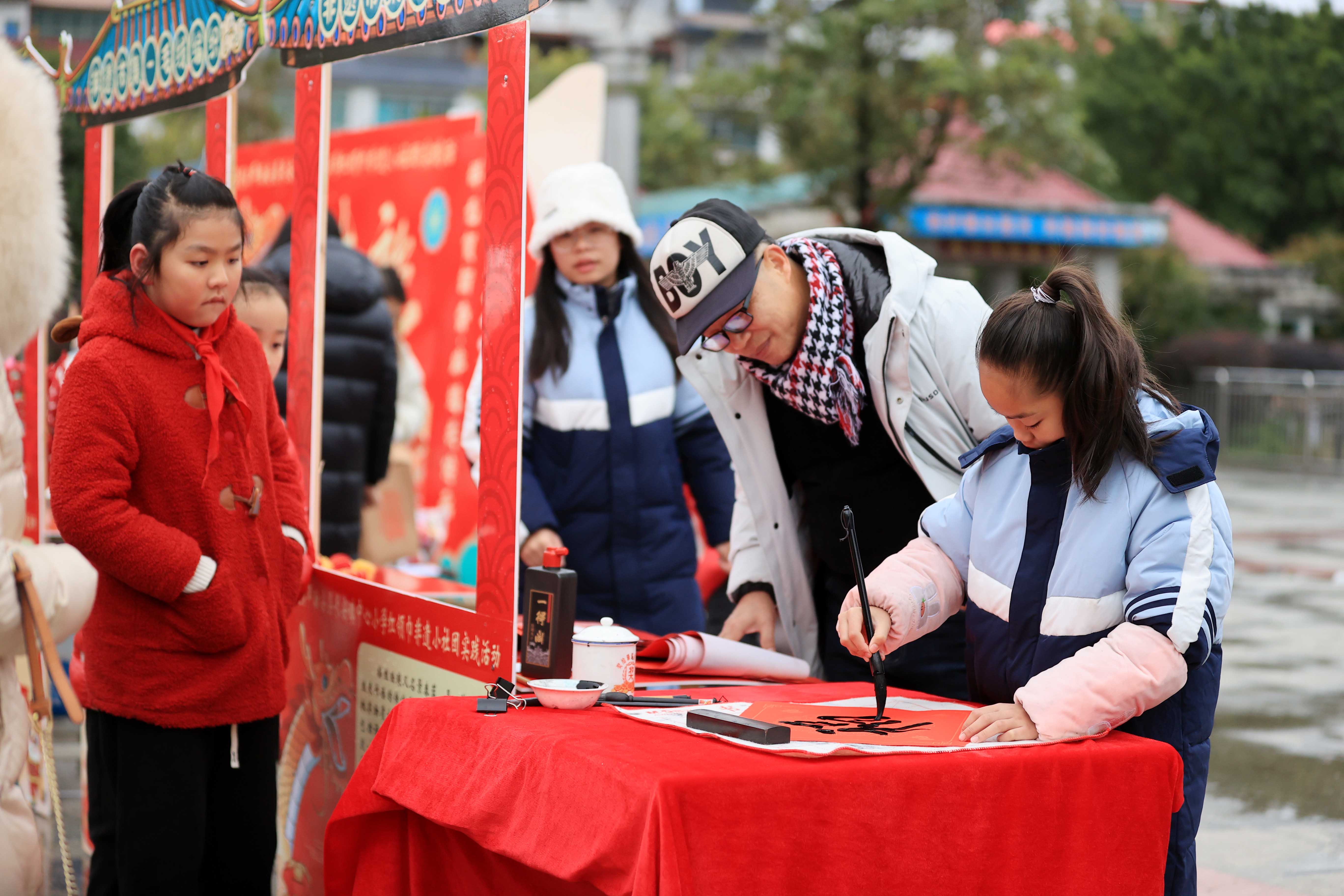 圖10：1月20日，在廣西柳州市融安縣長安廣場，一名小學(xué)生在書寫福字，準(zhǔn)備贈送市民。（譚凱興 攝）.JPG