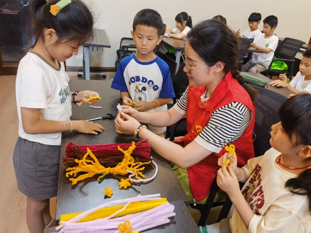 7月12日，在泰州市海陵區(qū)城東街道林湖社區(qū)，泰州市大浦小學(xué)“綠葉”暑期公益班的老師正在教孩子們一起做手工2（拍攝者：泰州市大浦中心小學(xué)  陳惠婷）.jpg